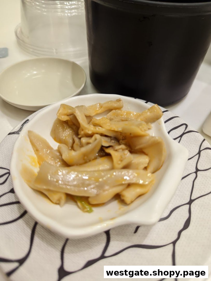 A close-up of a savory side dish, possibly marinated mushrooms or seafood, served in a white bowl.
