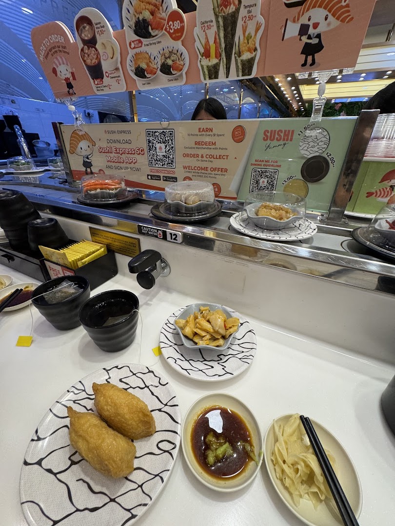 A vibrant interior shot of Sushi Express, showcasing a conveyor belt with various sushi dishes and promotional signage.