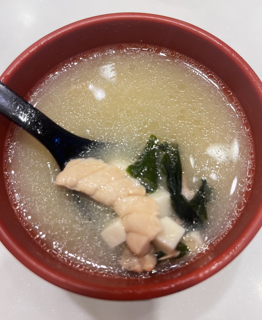 A close-up of a delicious bowl of miso soup with salmon, tofu, and seaweed.