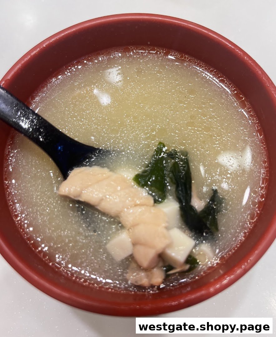 A close-up of a delicious bowl of miso soup with salmon, tofu, and seaweed.