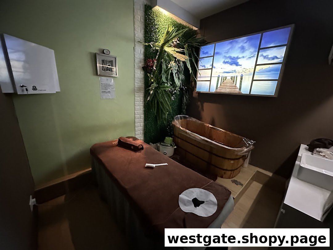 A serene spa treatment room featuring a massage bed, wooden tub, and scenic wall display.