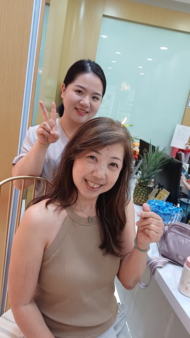Two smiling women, one staff, one customer, posing happily inside a bright shop.