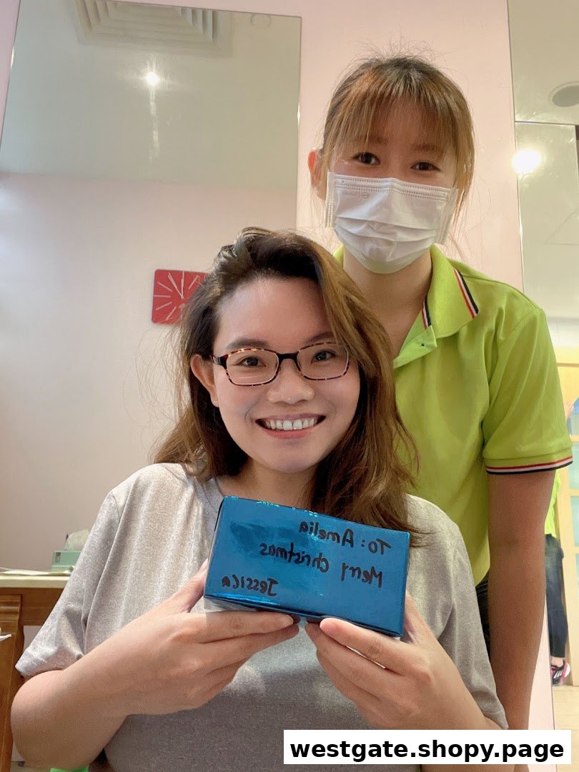 A happy customer holds a gift box with a smiling staff member in a salon setting.