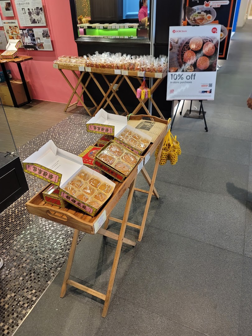 A shop entrance displaying mooncakes and other traditional pastries on wooden stands, with a promotional sign.