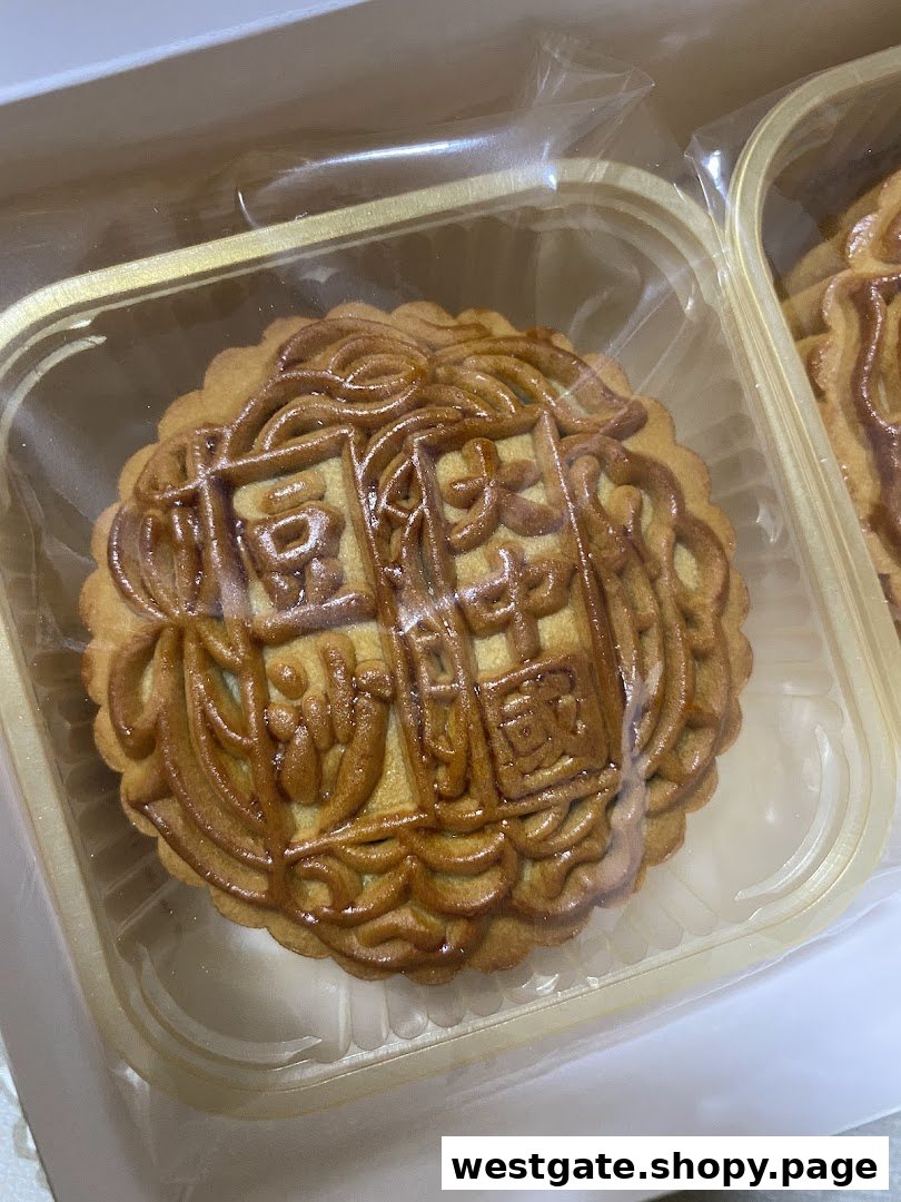 A close-up of a traditional mooncake with intricate patterns, packaged in a clear plastic tray.