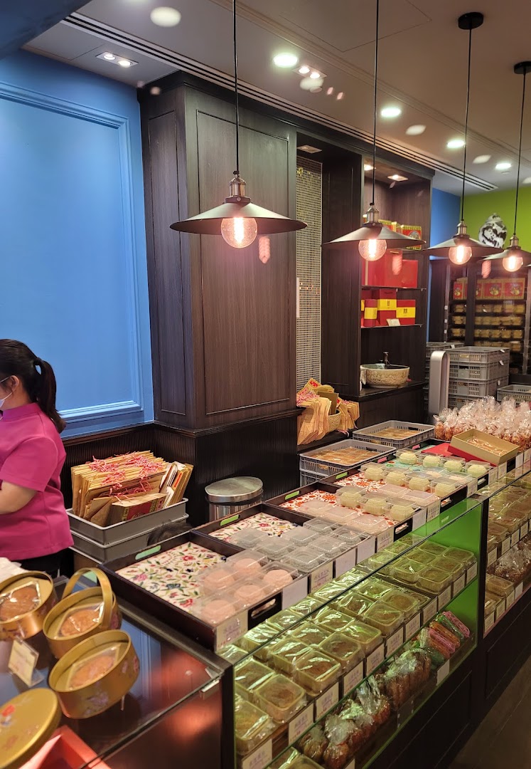 Interior view of Tai Chong Kok bakery showcasing a wide array of traditional pastries and a staff member.