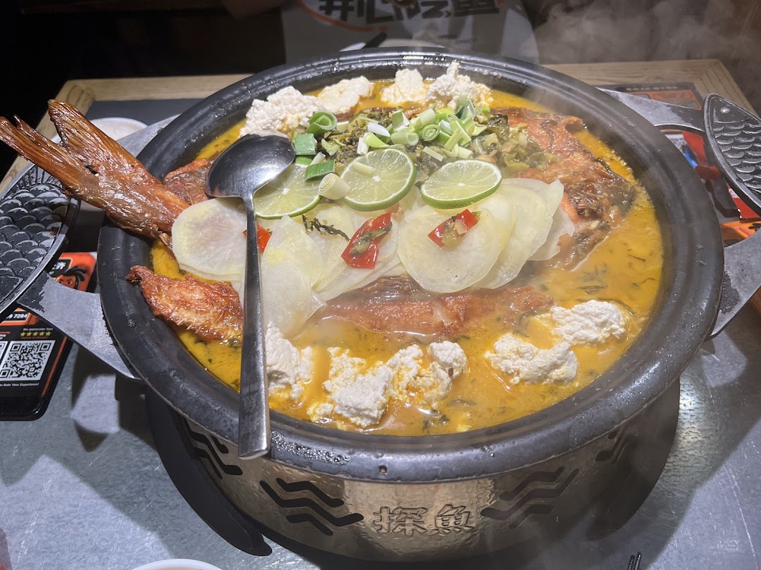 A large, steaming pot of grilled fish with lime, tofu, and vegetables, served on a table at TANYU.