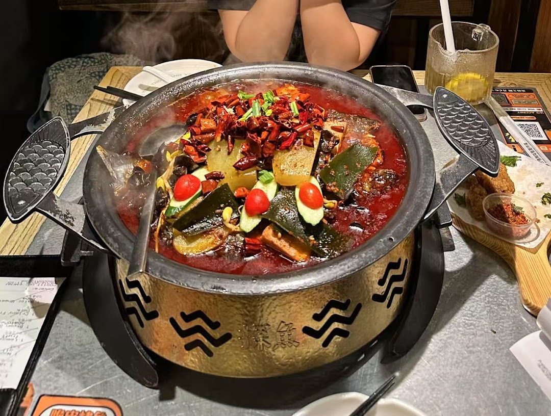 A steaming pot of spicy grilled fish with vegetables and chili, served on a table at TANYU Westgate.
