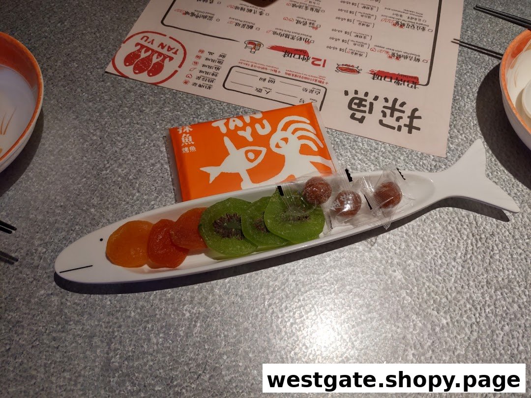 A table setting at TANYU featuring a fish-shaped dish with dried fruits, an orange box, and a menu.