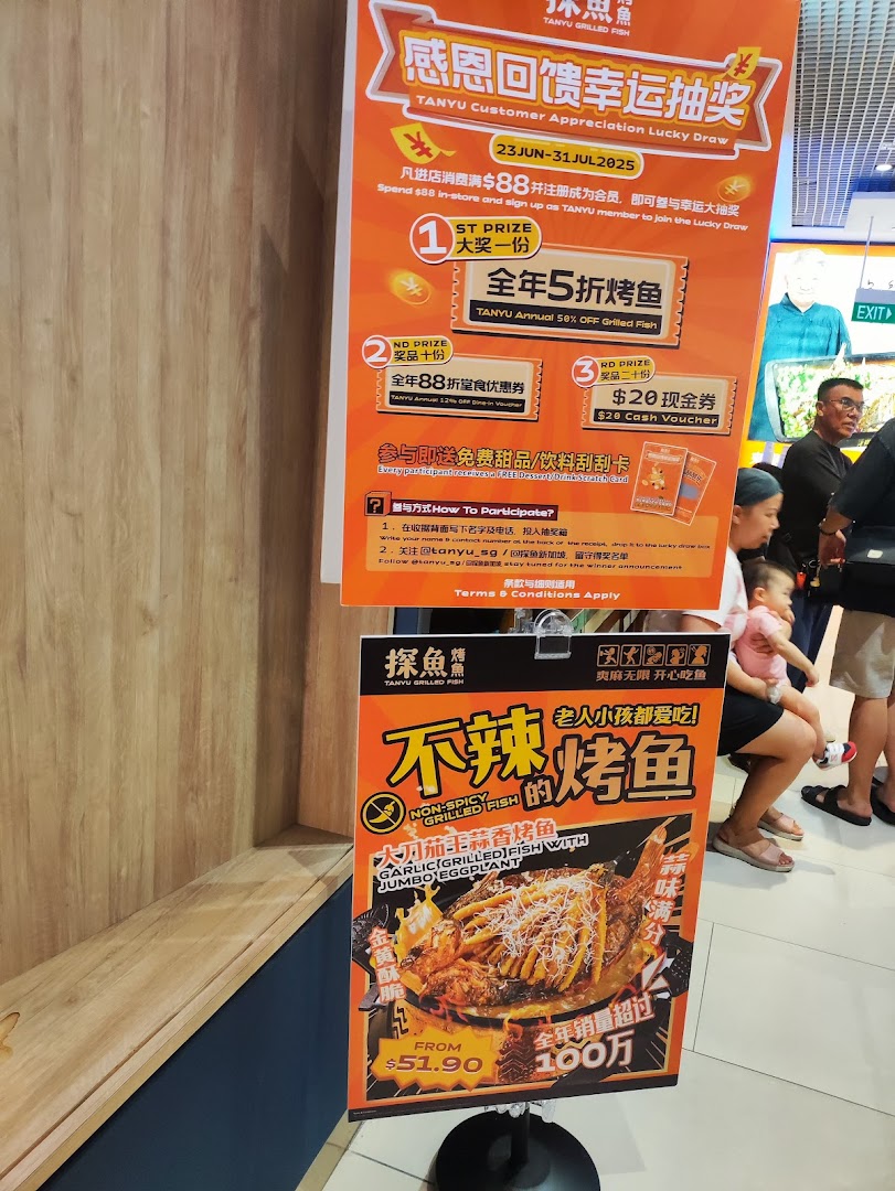 Promotional posters for TANYU Grilled Fish, featuring a customer lucky draw and a non-spicy dish.