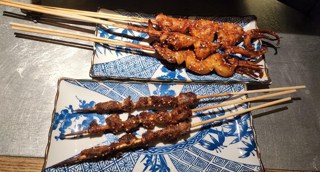 Two plates of delicious grilled skewers, featuring squid and meat, served on patterned dishes.