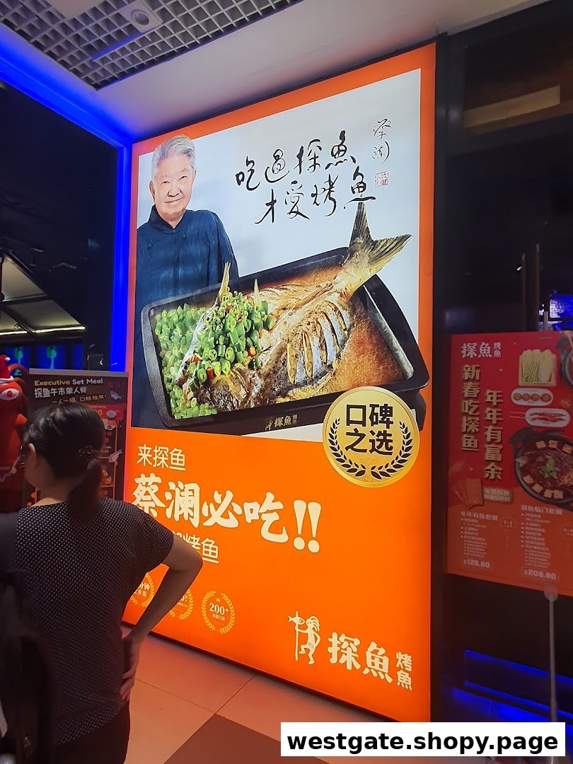 A large, vibrant orange promotional display for TANYU featuring a roasted fish dish, an elderly man, and Chinese text.