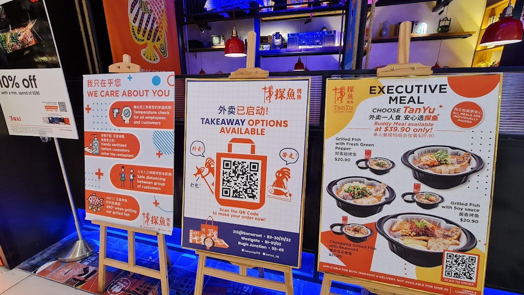 Promotional signs for TANYU Grilled Fish, featuring an executive meal offer and safety measures.