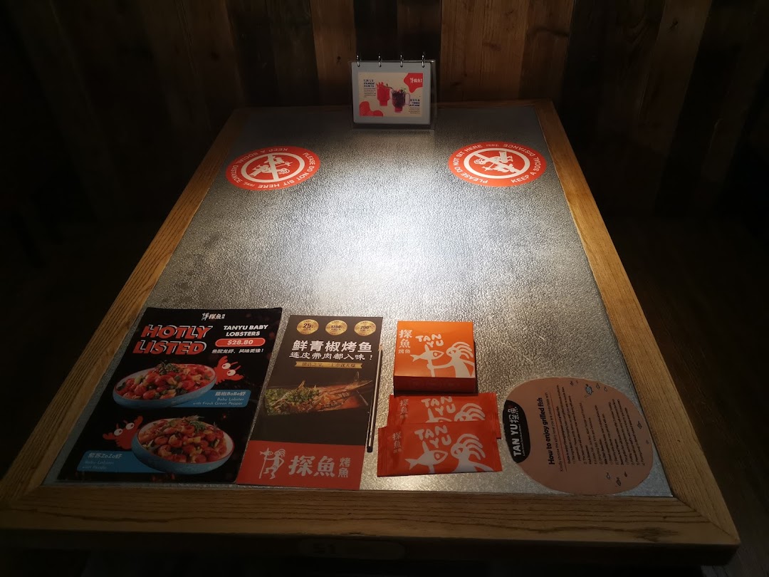 A restaurant table at TANYU Westgate featuring menus, branding, and social distancing reminders.