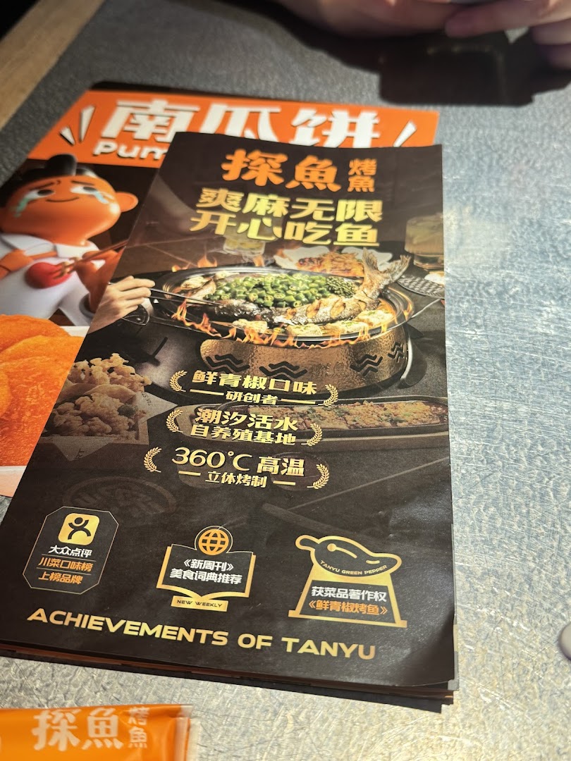 A promotional page for TANYU, showcasing their signature grilled fish, cooking methods, and culinary achievements.