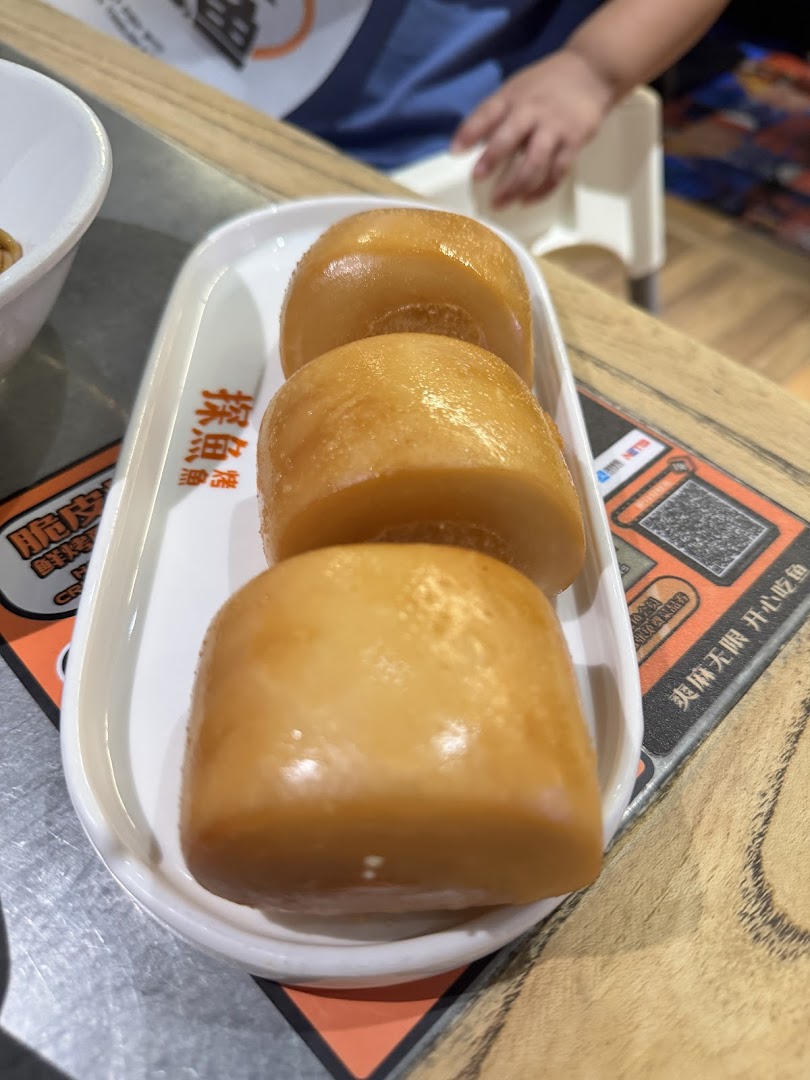 A plate of three golden-brown fried mantou buns, a popular side dish, served on a white rectangular plate.