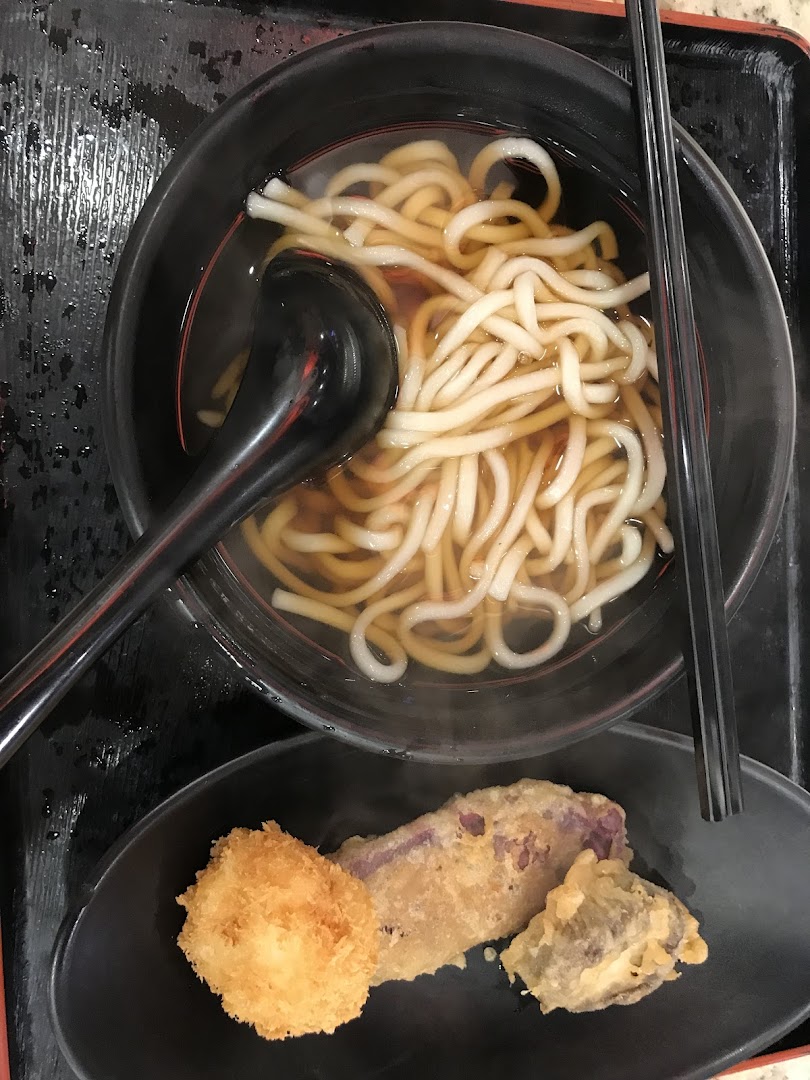 A close-up of a comforting bowl of udon noodles served with a side of crispy tempura.