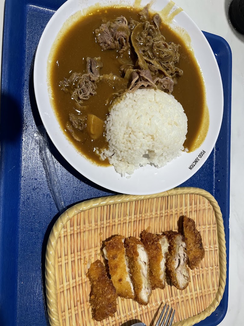 A plate of Japanese curry with beef and rice, served with a side of crispy fried chicken cutlets.