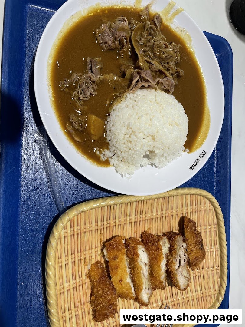 A plate of Japanese curry with beef and rice, served with a side of crispy fried chicken cutlets.