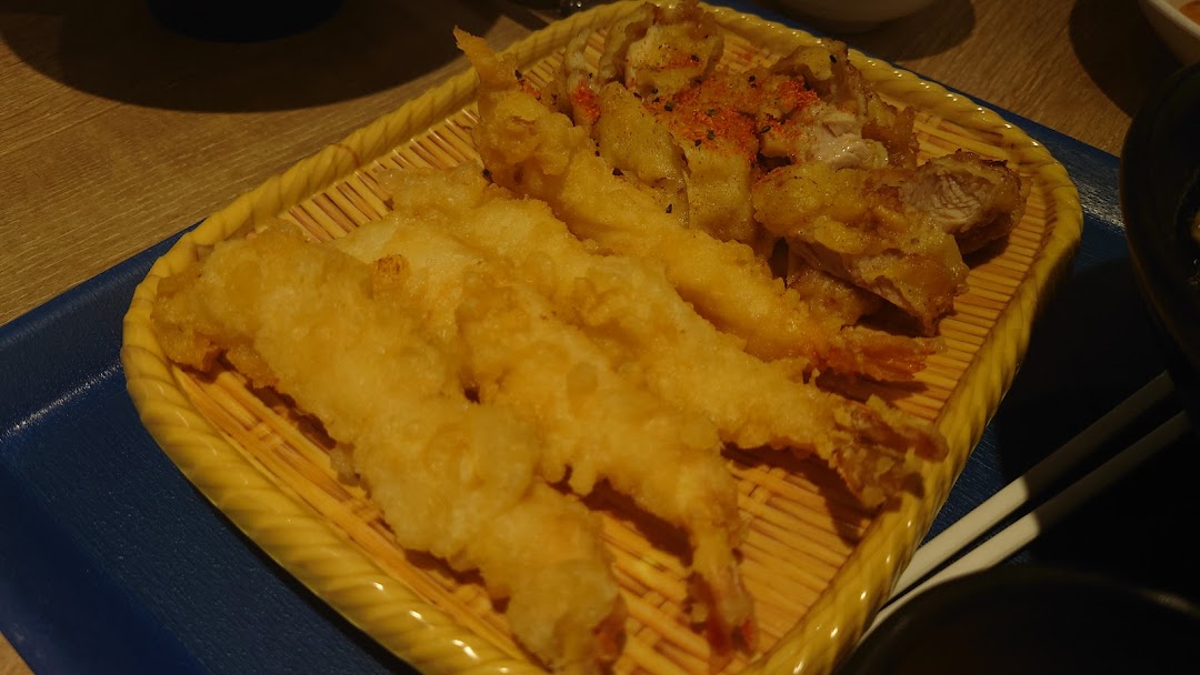 A close-up of golden-fried tempura shrimp and chicken on a traditional bamboo serving tray.