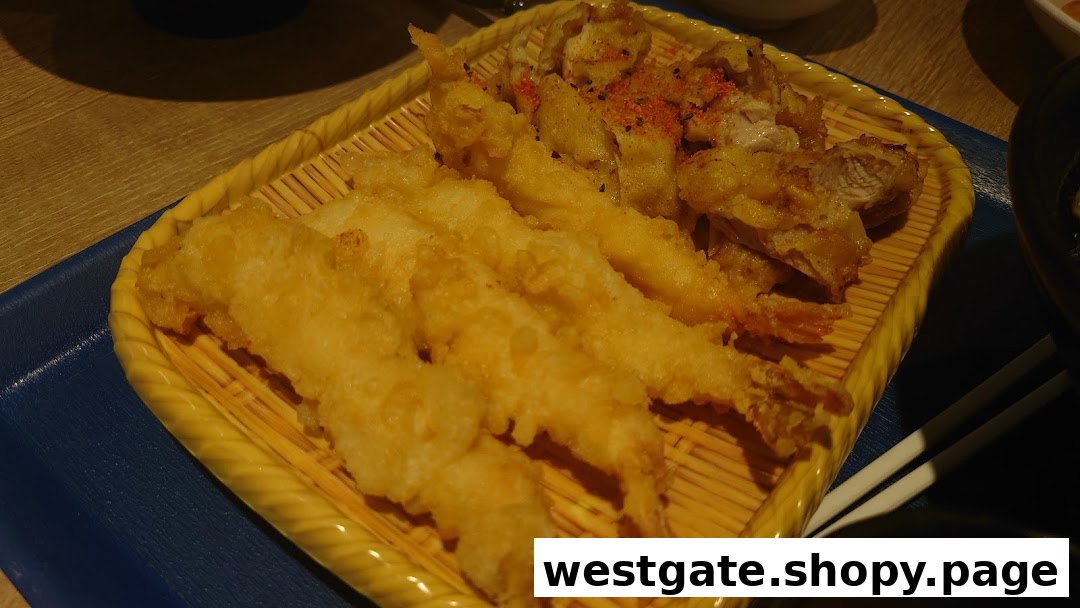 A close-up of golden-fried tempura shrimp and chicken on a traditional bamboo serving tray.