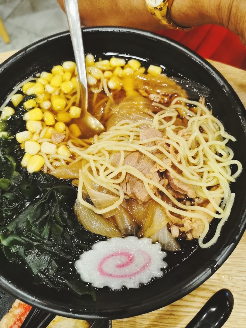 A close-up of a delicious bowl of ramen with noodles, corn, seaweed, meat, and a fish cake.