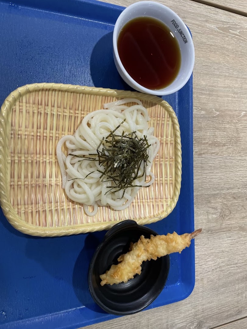 A delicious serving of cold udon noodles with seaweed, tempura shrimp, and dipping sauce.