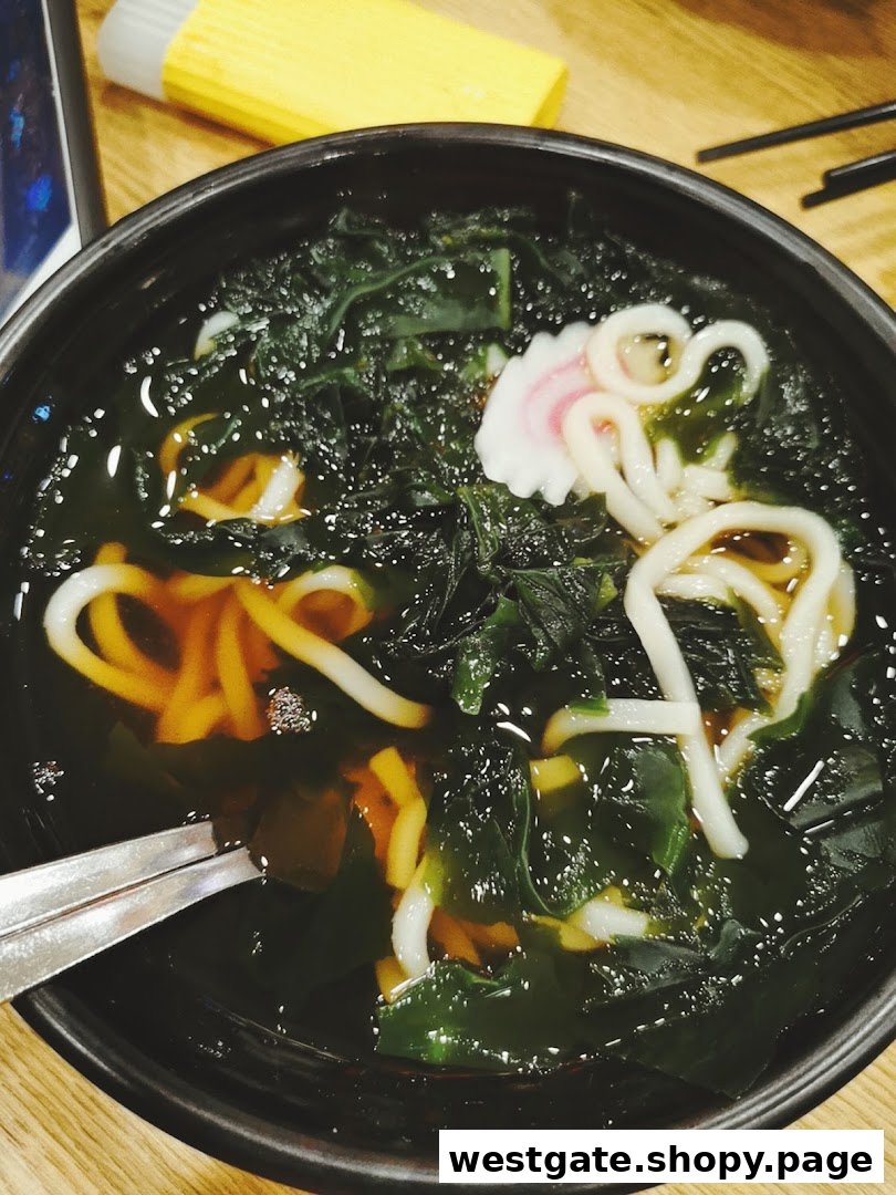 A close-up of a delicious bowl of udon noodles with seaweed and narutomaki fish cake.