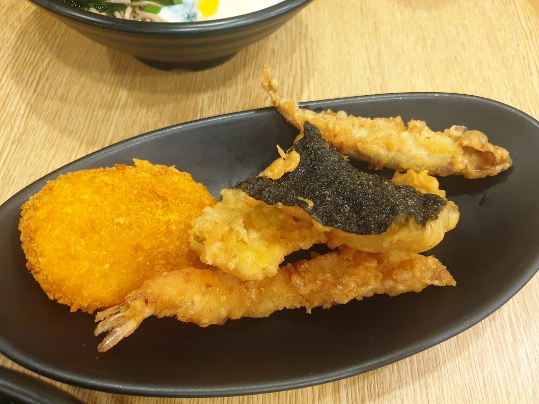 A close-up of a black plate featuring assorted golden-fried tempura, including shrimp, fish, and a croquette.