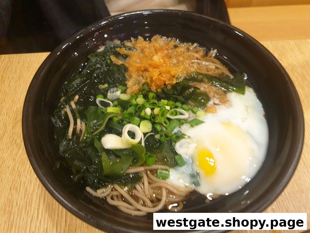 A close-up of a delicious Japanese noodle bowl with seaweed, green onions, tempura flakes, and a poached egg.