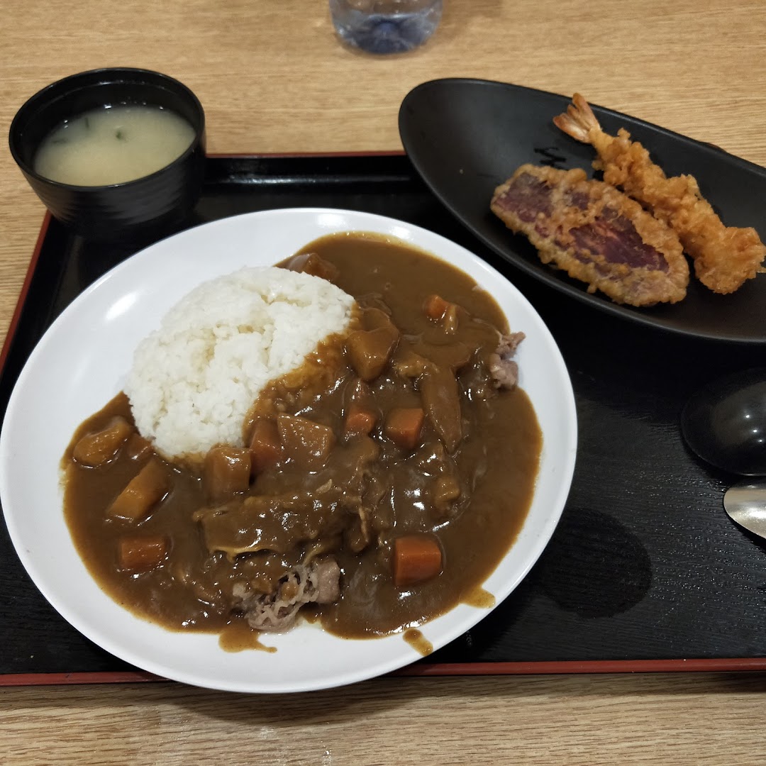 A delicious Japanese curry rice dish served with tempura and miso soup on a black tray.