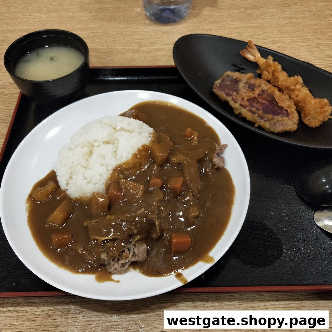 A delicious Japanese curry rice dish served with tempura and miso soup on a black tray.