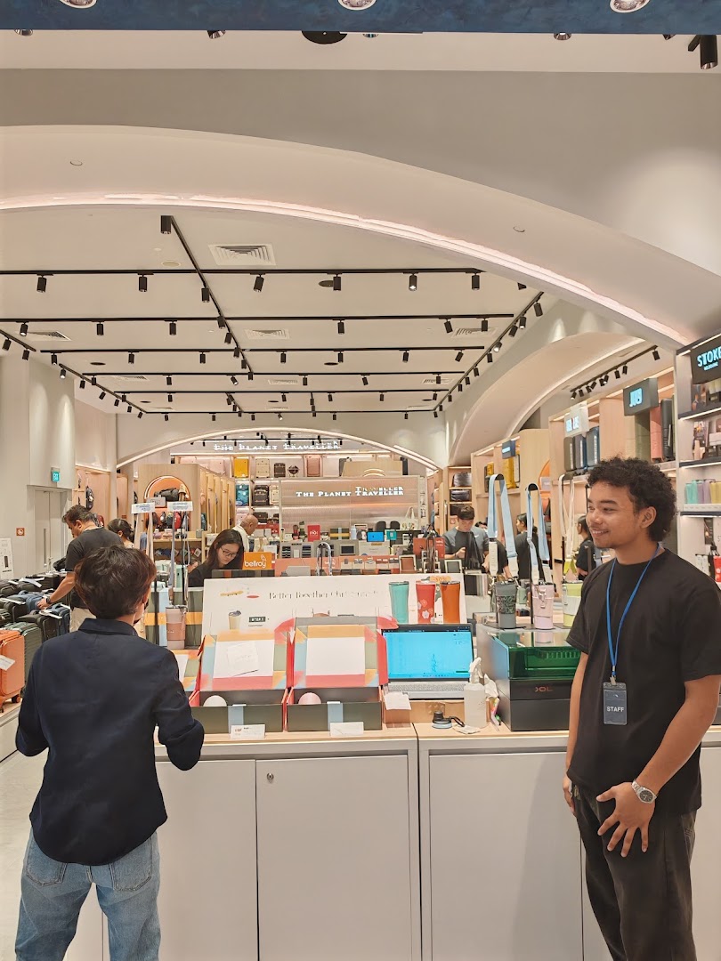 An interior view of The Planet Traveller shop, showcasing travel accessories and staff assisting customers.
