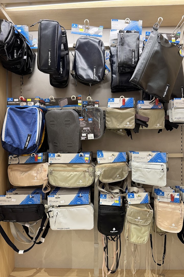 A display wall showcasing various Eagle Creek travel accessories, including packing cubes, pouches, and security wallets.