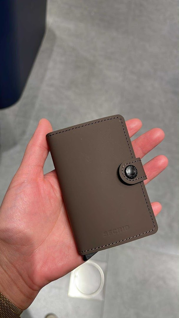 A hand holding a brown Secrid wallet, showcasing its design and texture.