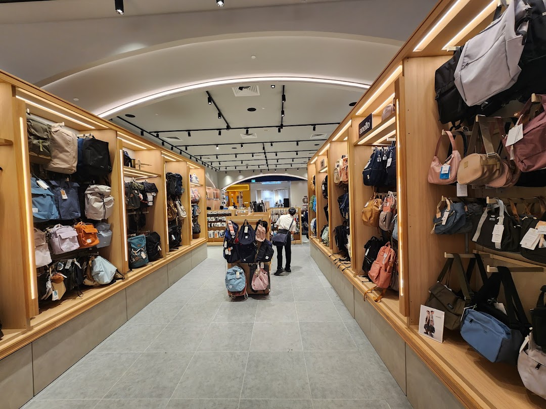 An interior view of The Planet Traveller store, showcasing a wide array of bags and backpacks on illuminated wooden shelves.