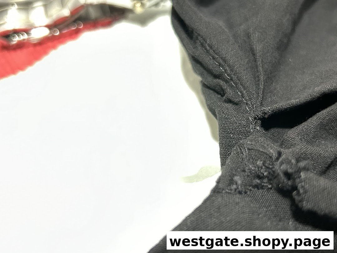 Close-up of black fabric with visible stitching, possibly clothing, against a white background.