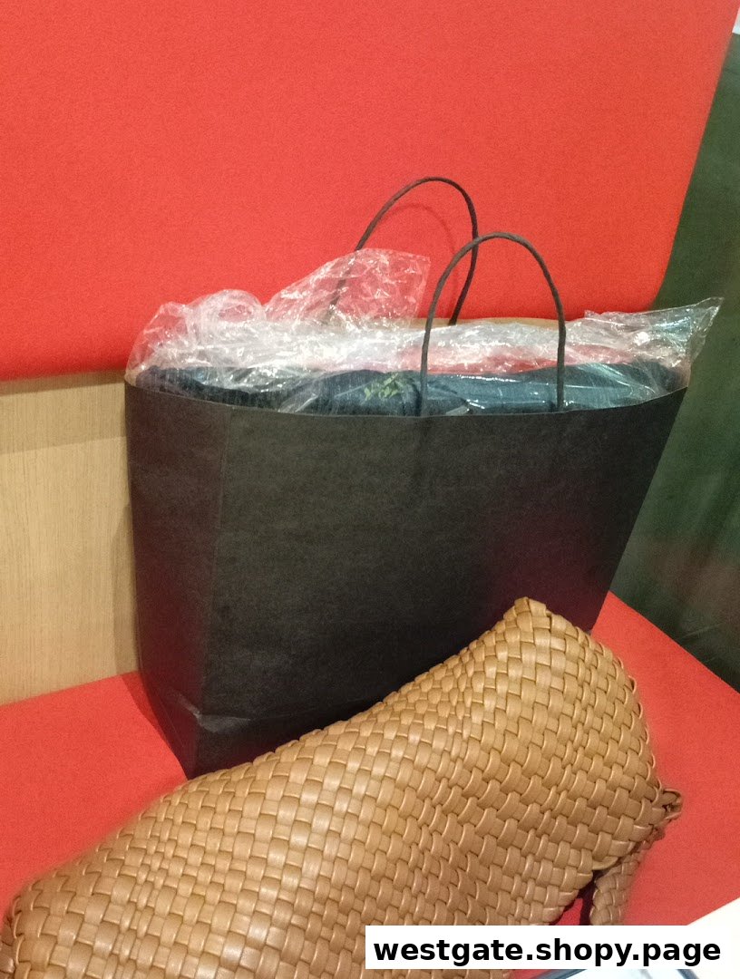 A black shopping bag and a woven brown clutch on a vibrant red surface.