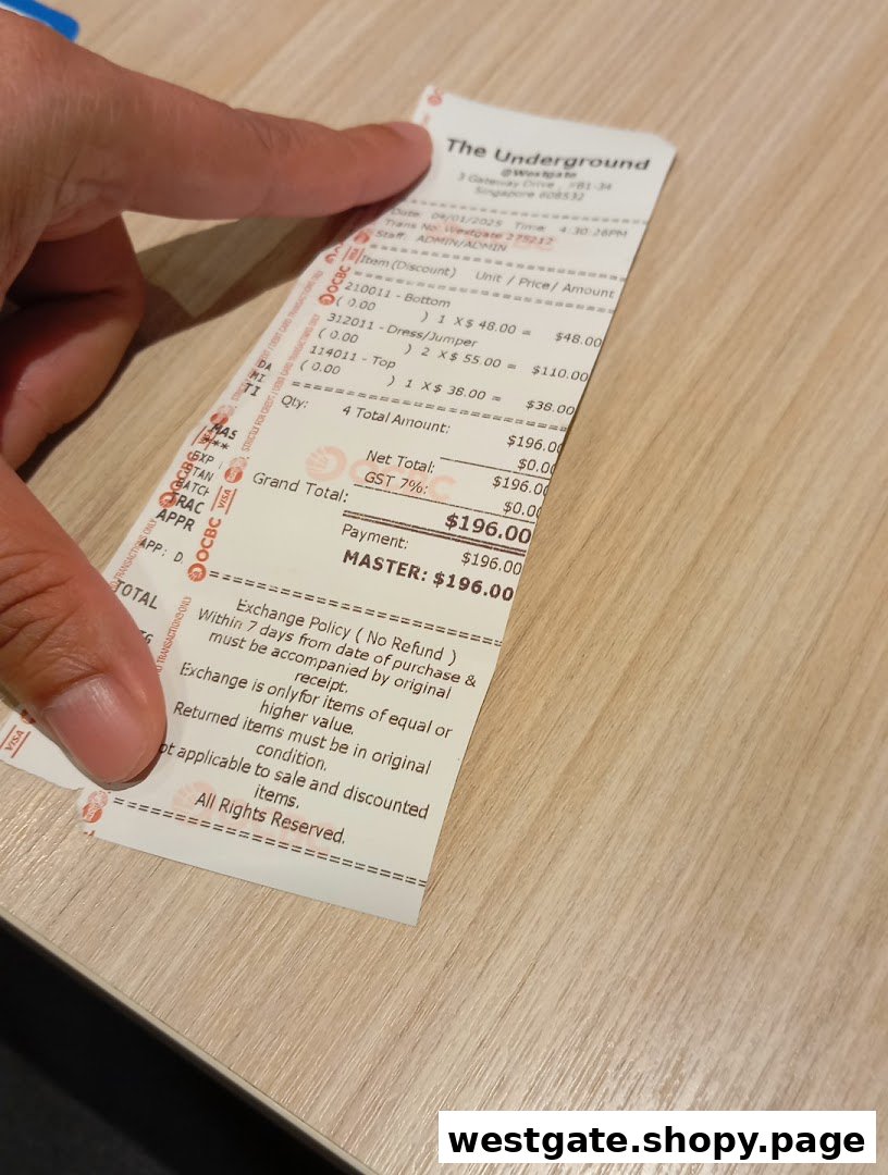 A hand holds a detailed shopping receipt from The Underground, showing clothing purchases.