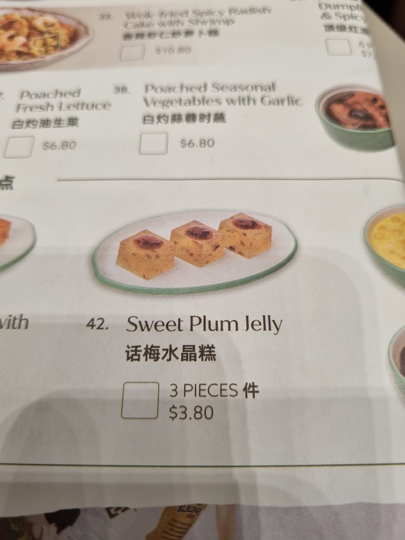 A close-up of Tim Ho Wan's menu, showcasing dim sum items like Sweet Plum Jelly and Poached Vegetables with prices.