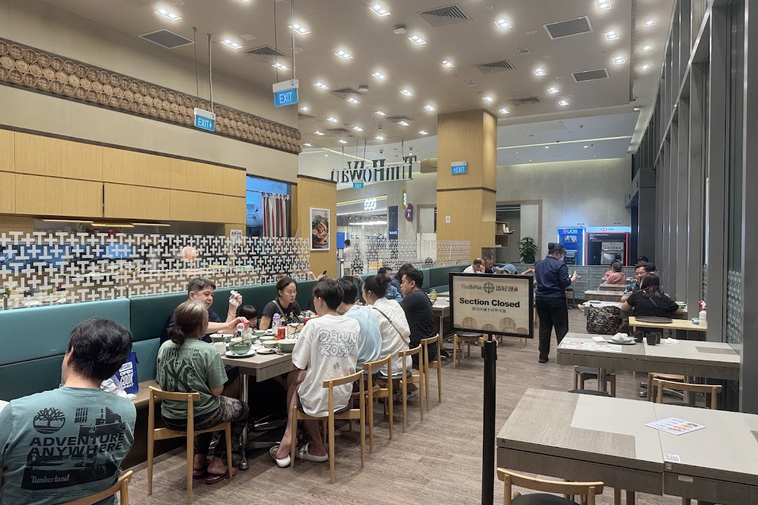 Diners enjoying a meal inside the bustling Tim Ho Wan restaurant, featuring a modern interior.