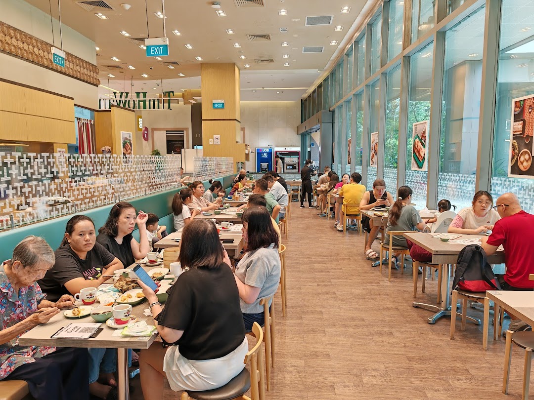 A bustling Tim Ho Wan restaurant interior with customers enjoying dim sum at various tables.
