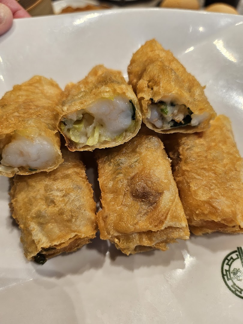 A plate of golden-fried spring rolls, some cut open to reveal succulent shrimp and vegetables inside.