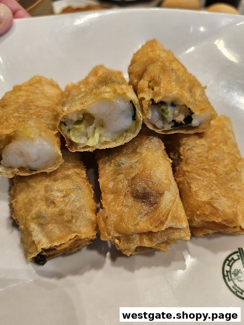 A plate of golden-fried spring rolls, some cut open to reveal succulent shrimp and vegetables inside.