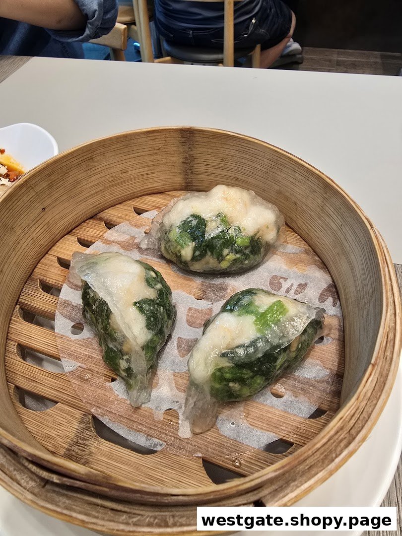 Three steamed dumplings with translucent skin and green filling served in a traditional bamboo steamer.