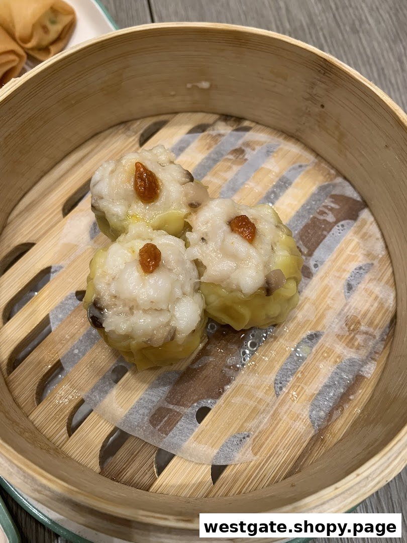 Three delicious dim sum pieces, possibly siew mai, served in a traditional bamboo steamer basket.