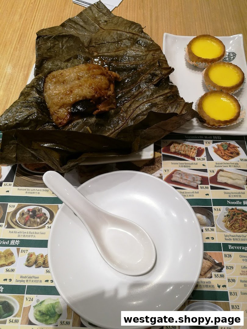 Dim sum dishes, including lotus leaf wrapped glutinous rice and egg tarts, on a table with a partial menu.