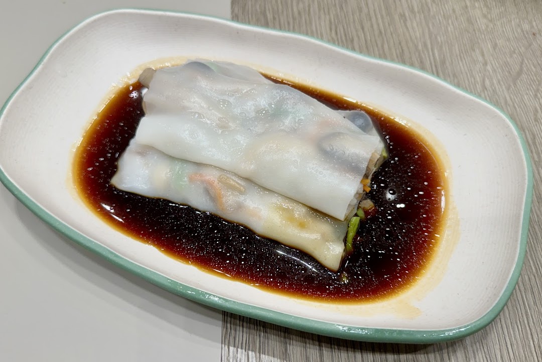 A close-up of delicious rice noodle rolls (Cheung Fun) served with savory soy sauce.