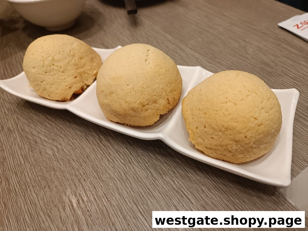 Three golden-baked buns, likely Tim Ho Wan's famous BBQ pork buns, served on a white plate.
