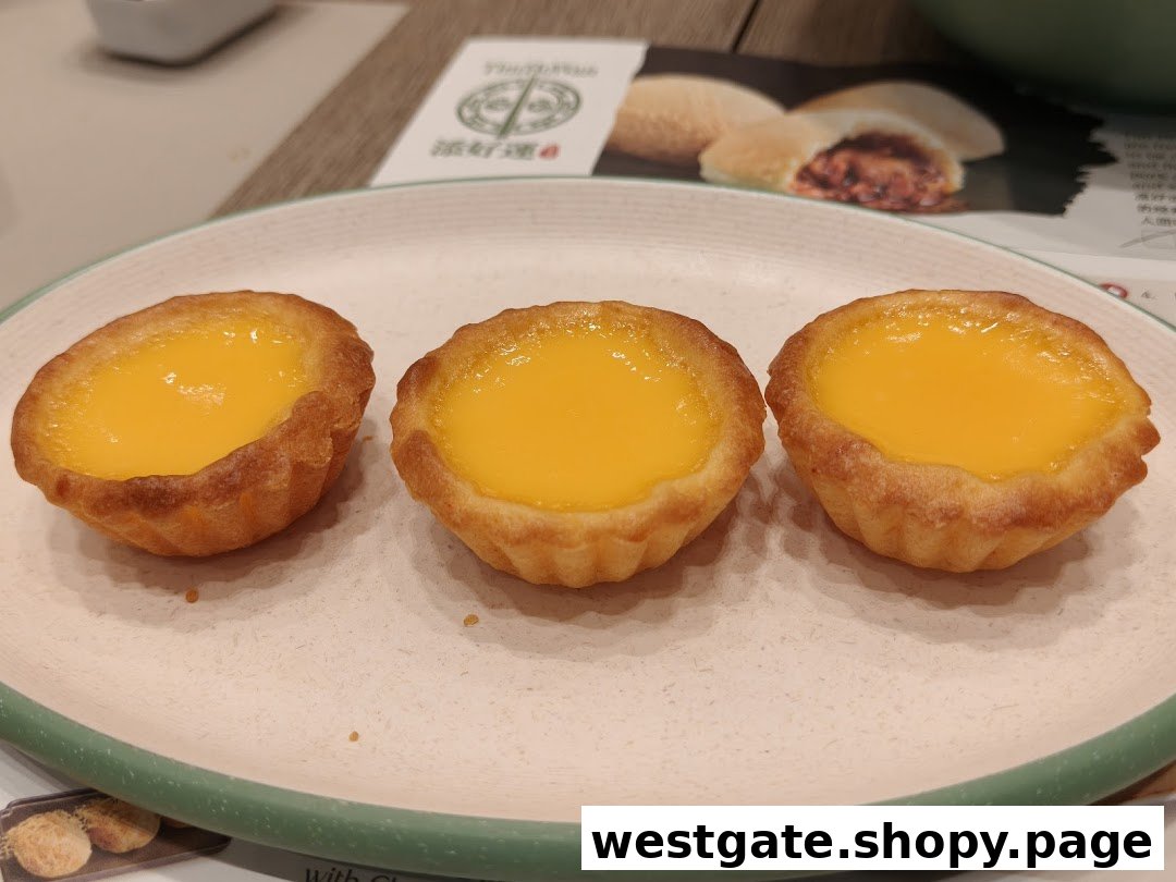 Three golden egg tarts on a plate, with a Tim Ho Wan menu visible in the background.